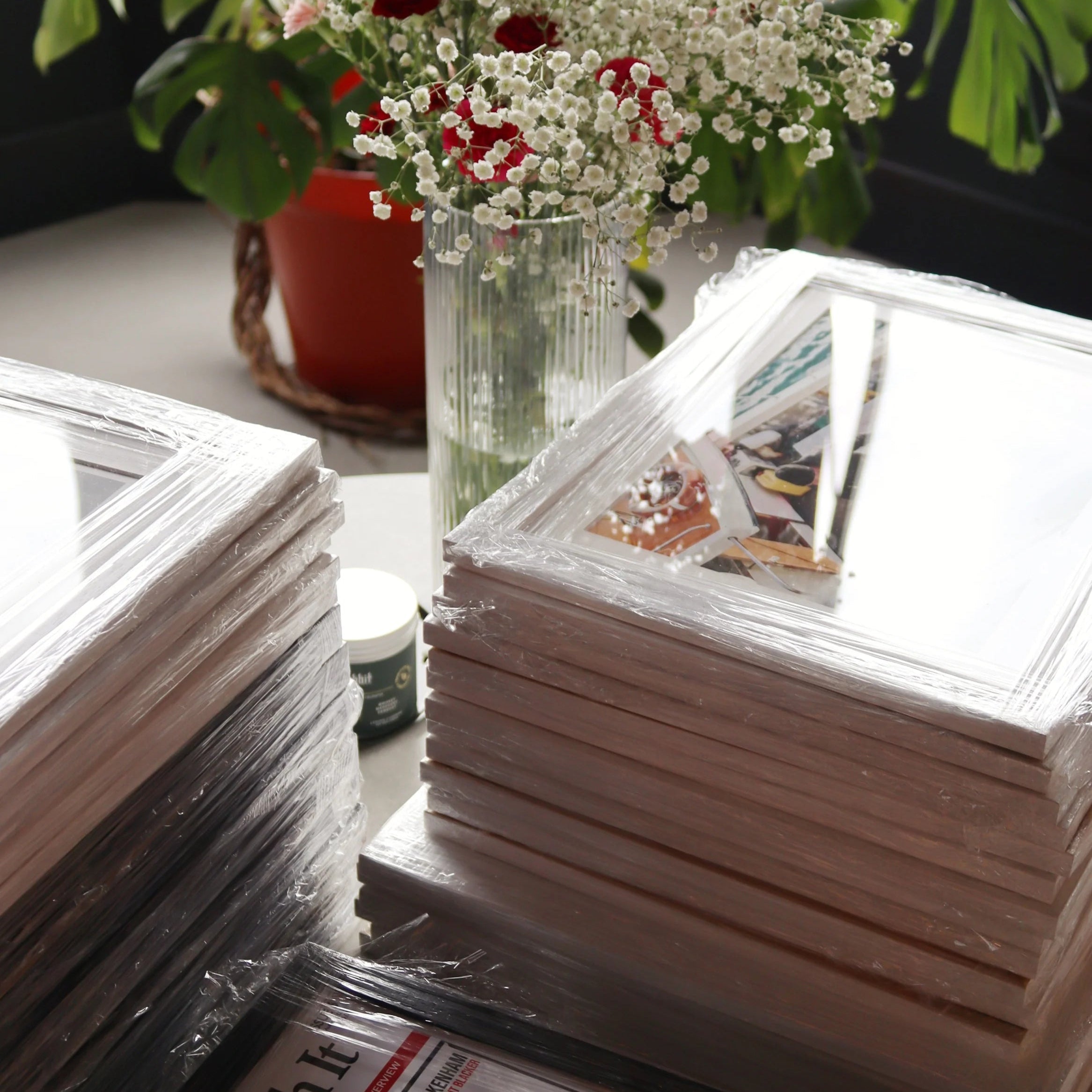 Stacks of photo albums on a table with flowers in the background